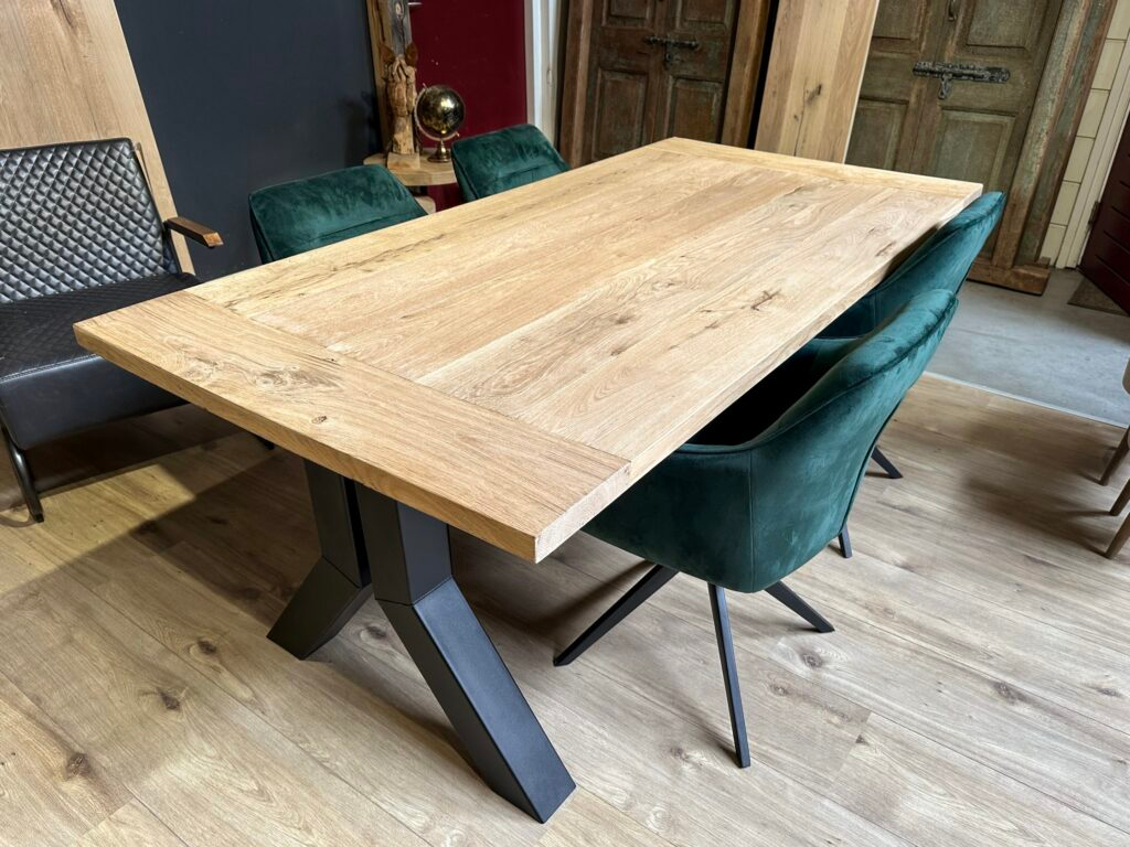 Tafelblad eiken ingelegd, met twee zwart stalen brugpoten eronder en 4 kuipstoelen aan de tafel